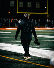 Dynamic shot of a football creator filming content on a stadium pitch at dusk.
