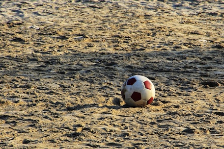 A close-up of a futevôlei ball on the sand, ready for play.