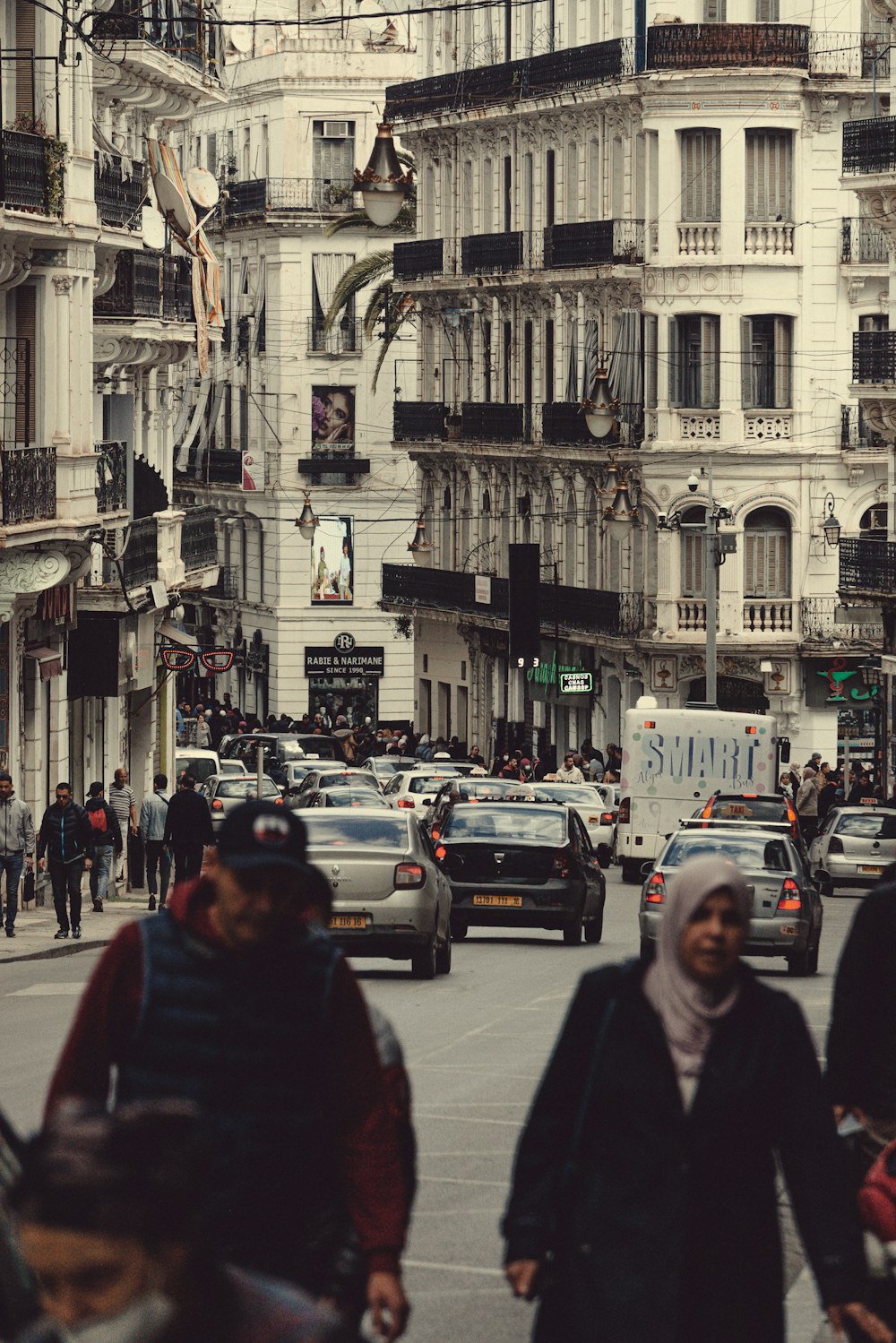 a group of people walking down a street next to tall buildings