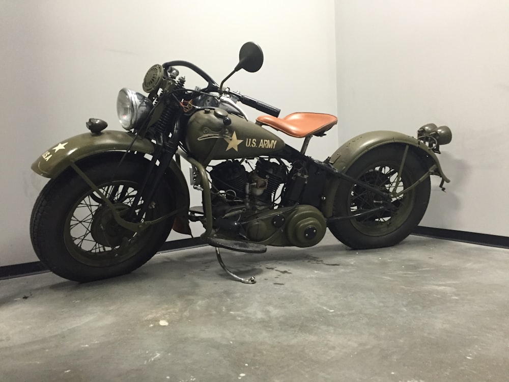 a green motorcycle parked in a garage next to a wall