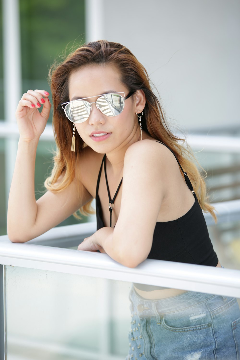 a woman wearing sunglasses leaning on a rail