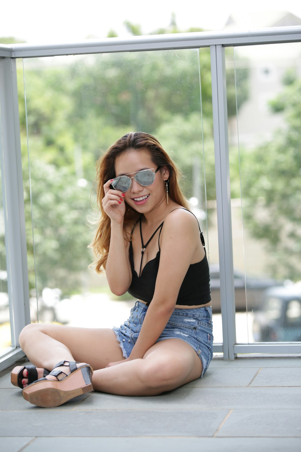 a woman sitting on the ground with a pair of sunglasses