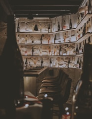 A cozy, dimly lit wine cellar with wooden shelves lined with bottles and a small tasting table.