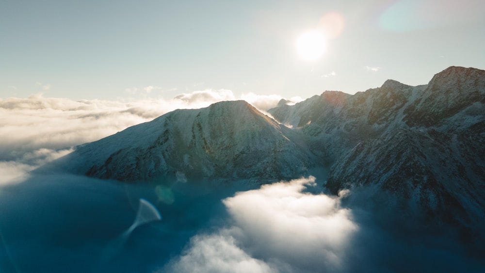a bird flying over a mountain covered in clouds