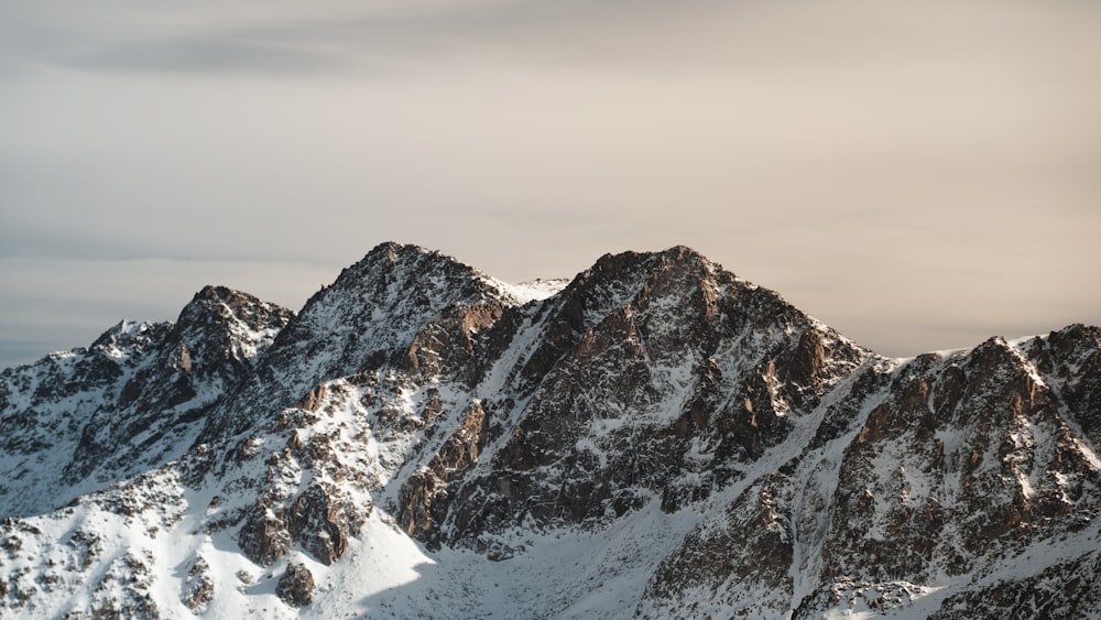 a group of mountains covered in snow under a cloudy sky