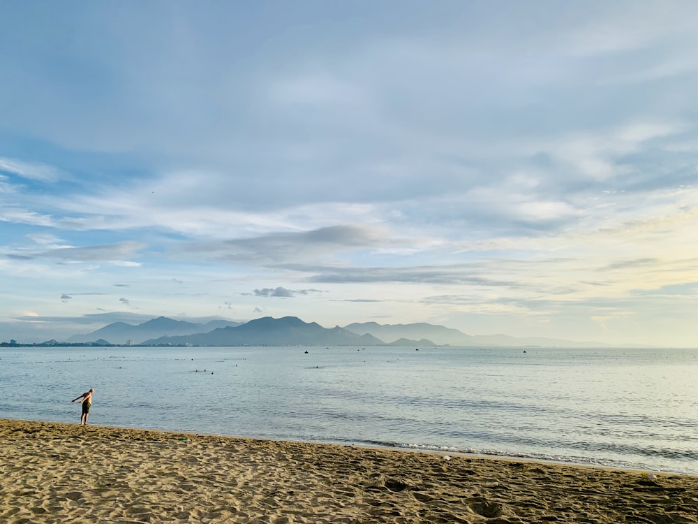 a person standing on a beach flying a kite