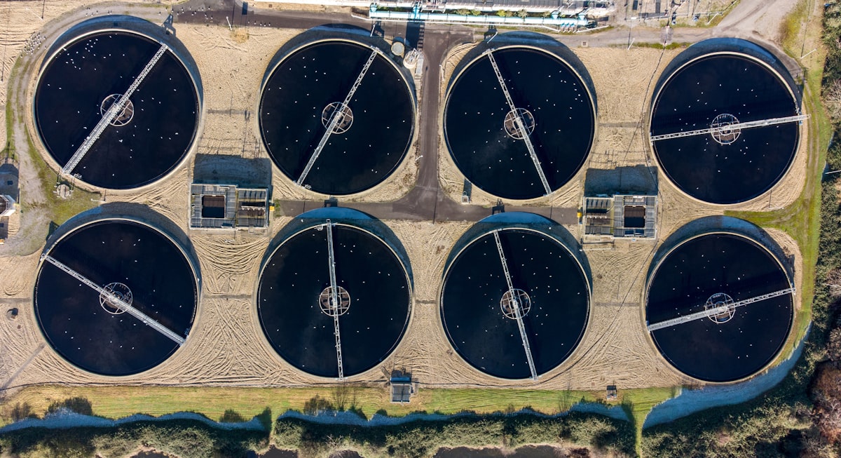 Aerial view of an industrial water treatment plant with multiple tank arrays and process buildings — Photo: Bob Brewer / Unsplash
