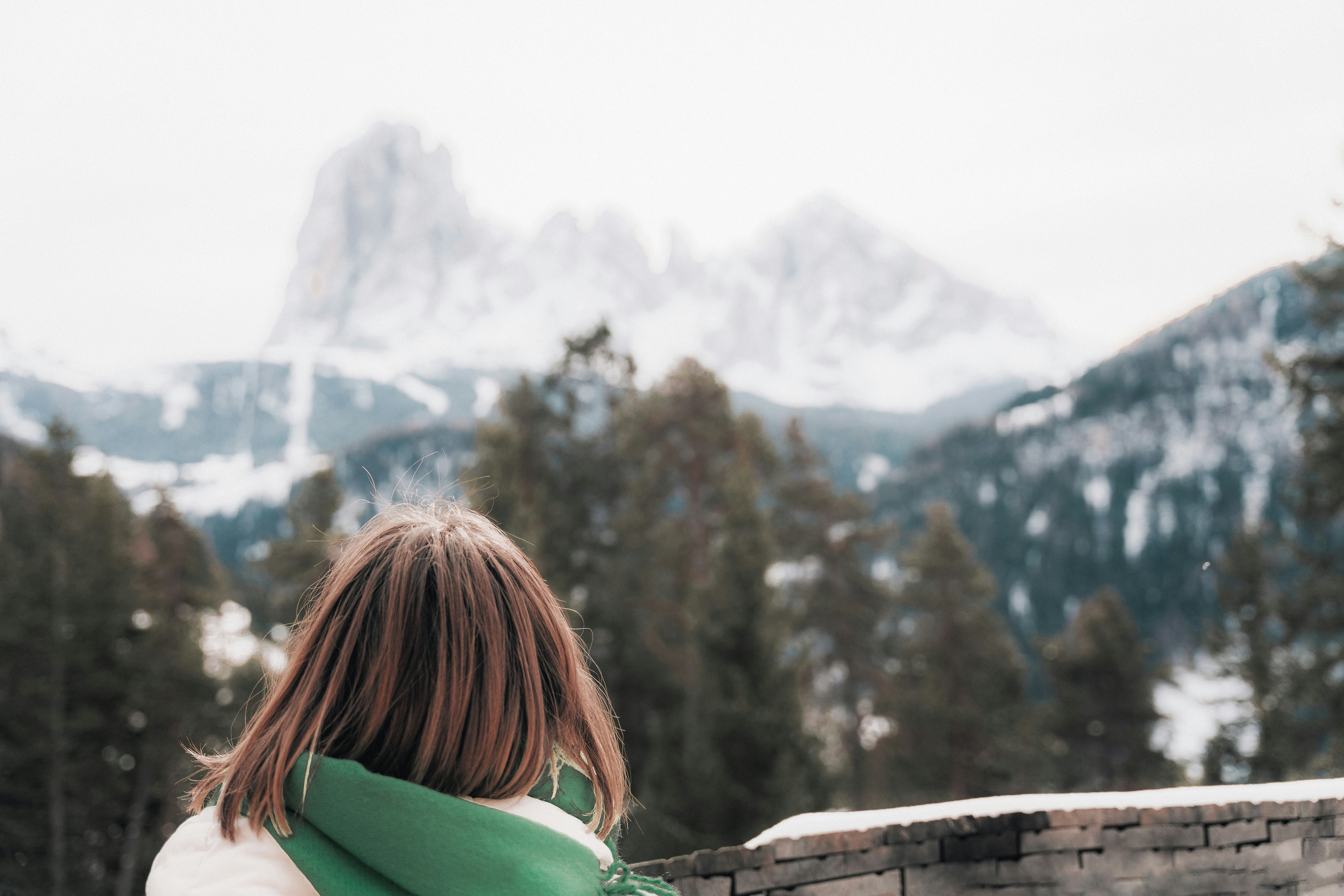 a woman wearing a green scarf standing in front of a mountain