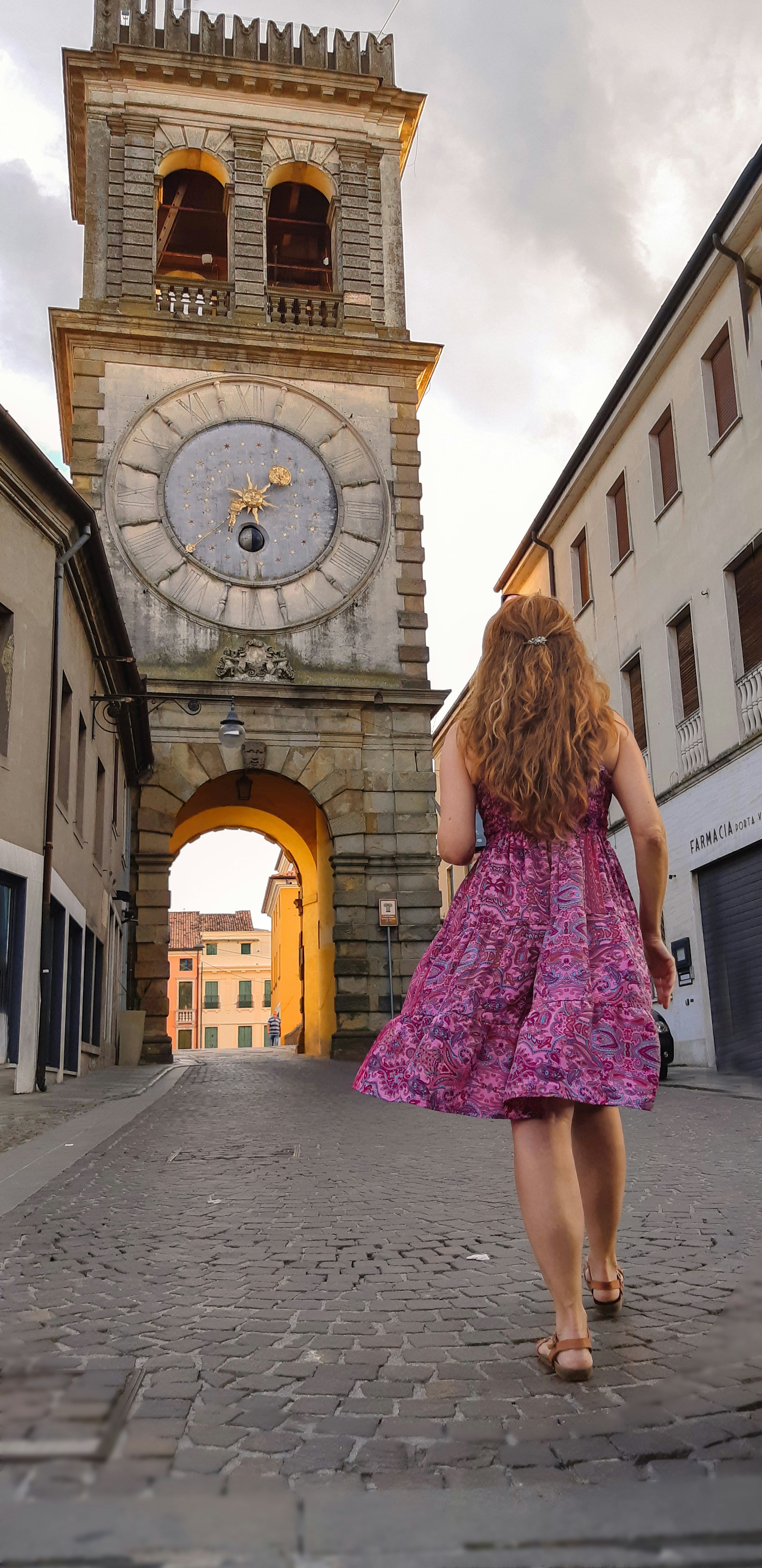 a woman in a purple dress walking towards a clock tower