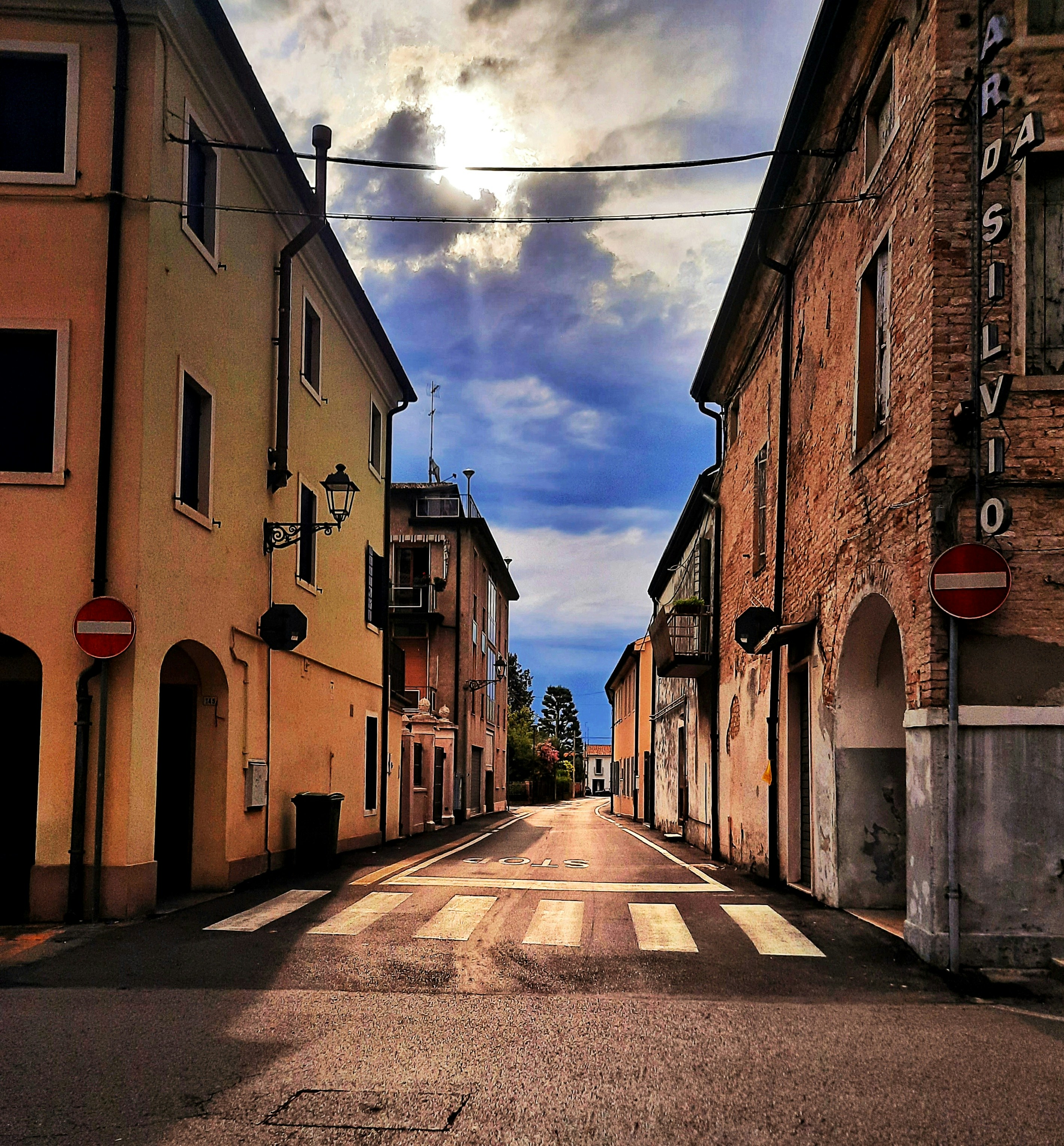 an empty street with buildings and a cloudy sky