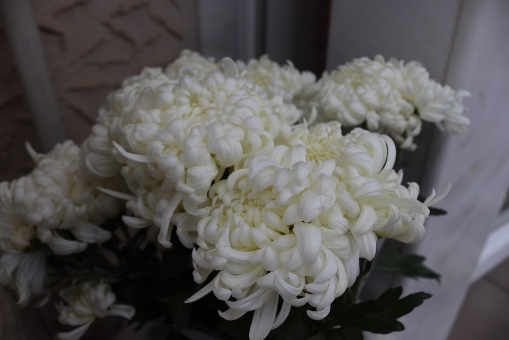 un vaso pieno di fiori bianchi in cima a un tavolo