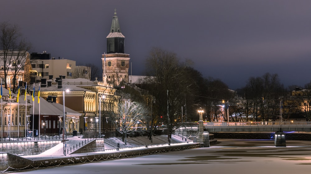 a night scene of a city with a clock tower in the background