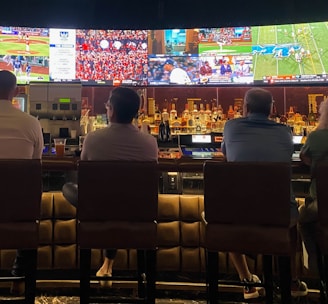 a group of people sitting at a bar watching tv