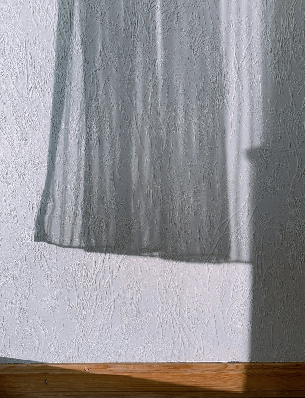 a shadow of a curtain on a wall
