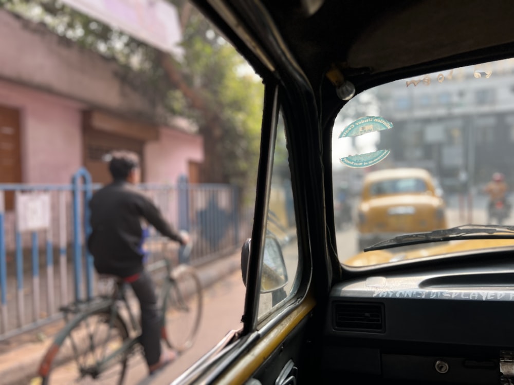 a man riding a bike down a street next to a yellow taxi