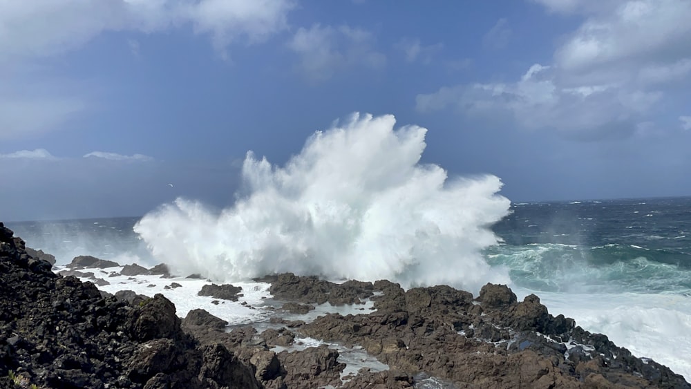 a large wave crashing over a rocky shore