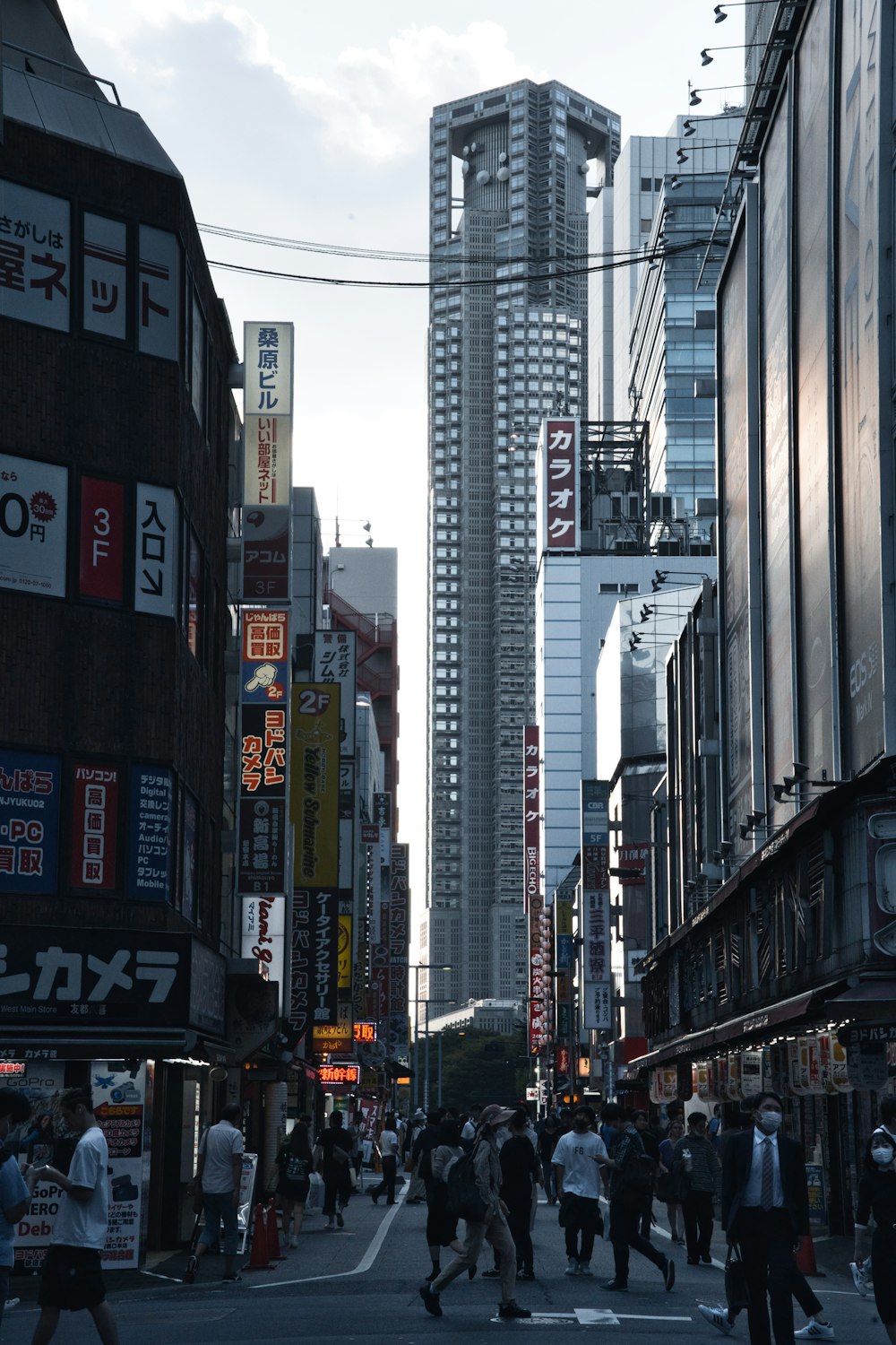 a group of people walking down a street next to tall buildings