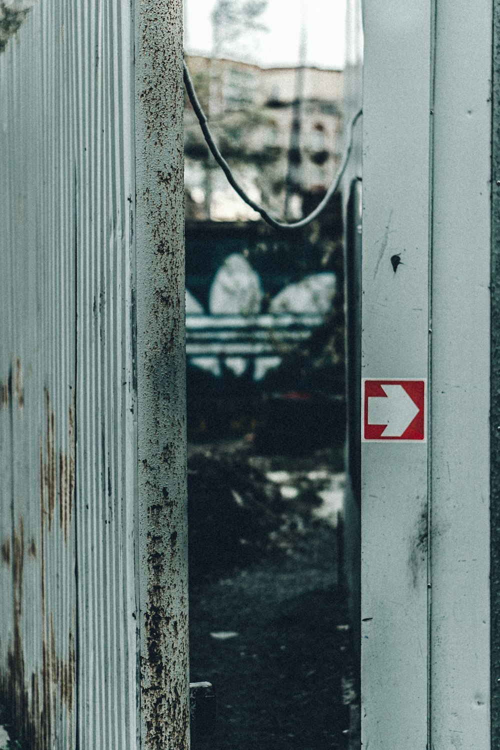 a rusted metal door with a red arrow sign on it