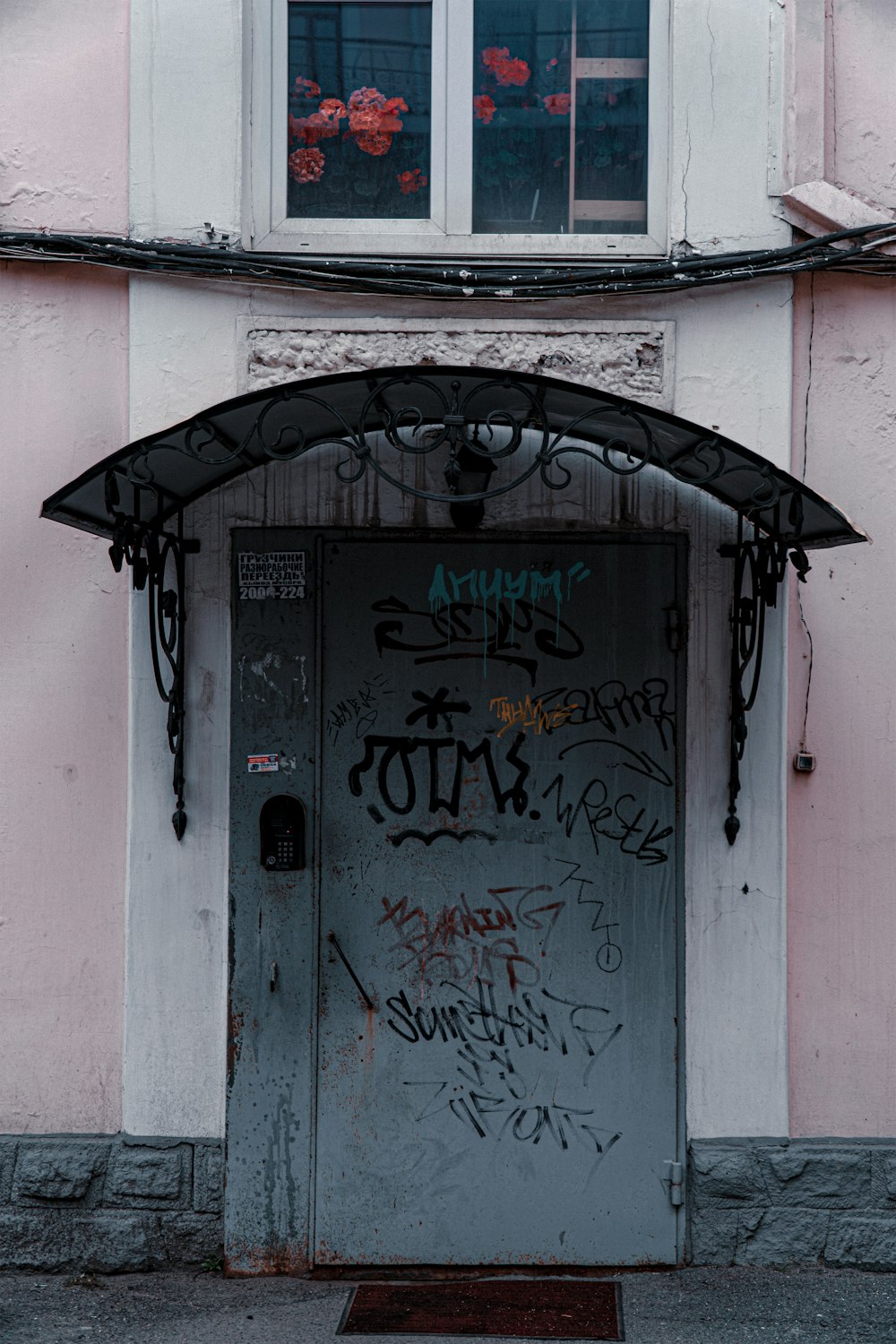 a door with graffiti on it in front of a pink building