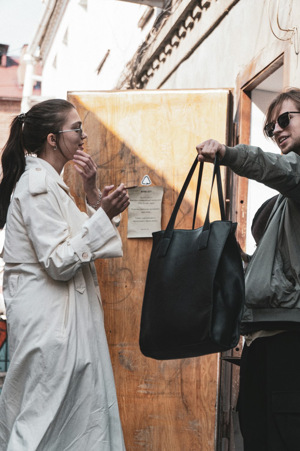 a woman holding a black bag next to another woman