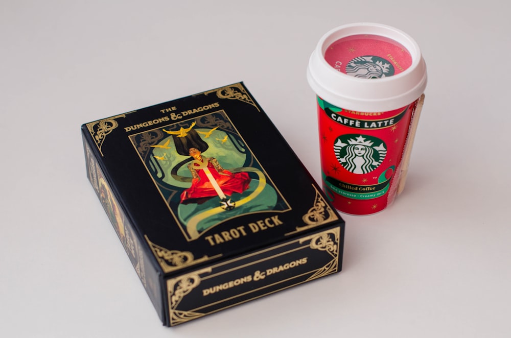 a starbucks coffee cup next to a tarot deck box