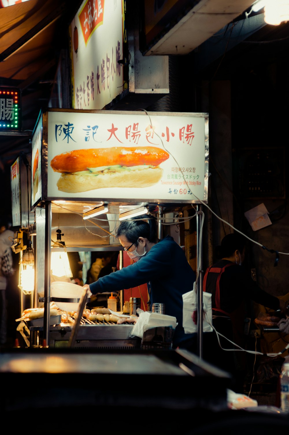 a man standing in front of a hot dog stand