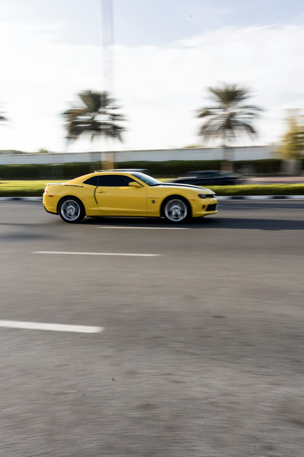 a yellow sports car driving down a street