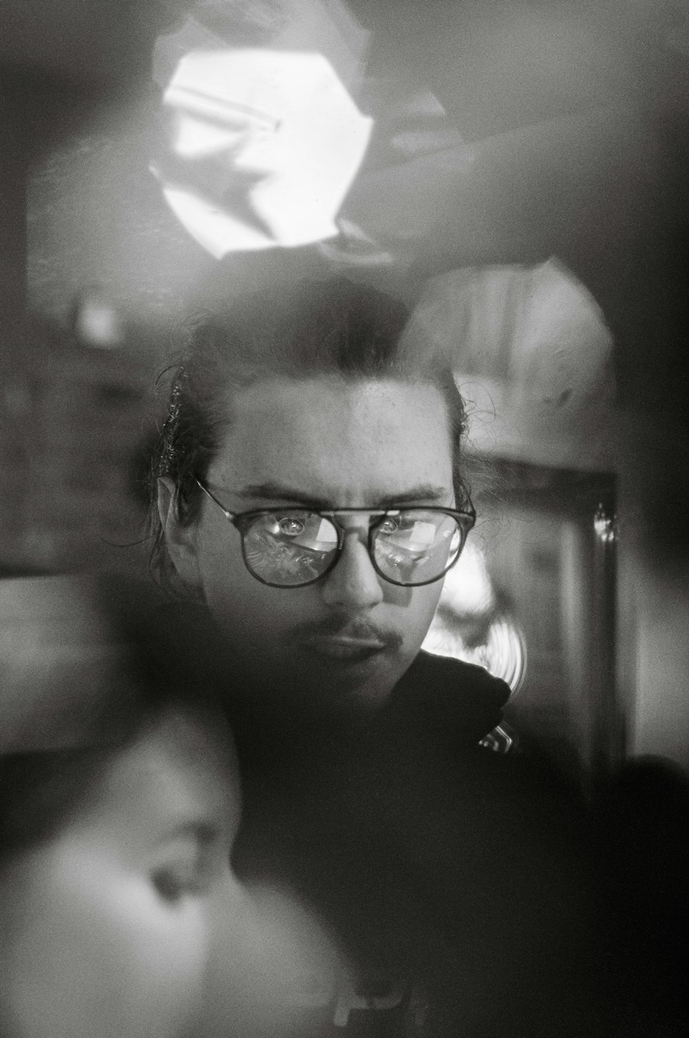 a man with glasses looking at his reflection in a mirror