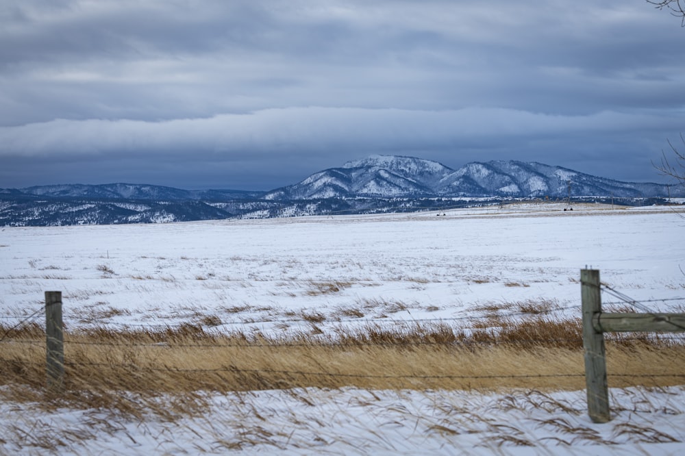 a snow covered field with mountains in the distance