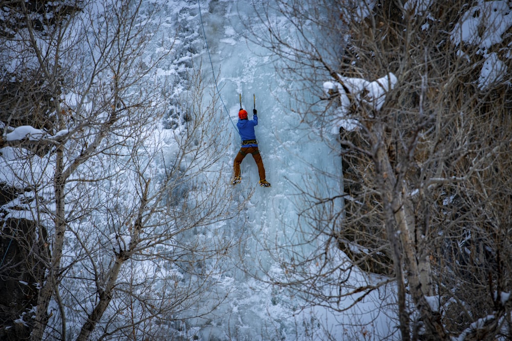 a man standing on a frozen waterfall in the woods