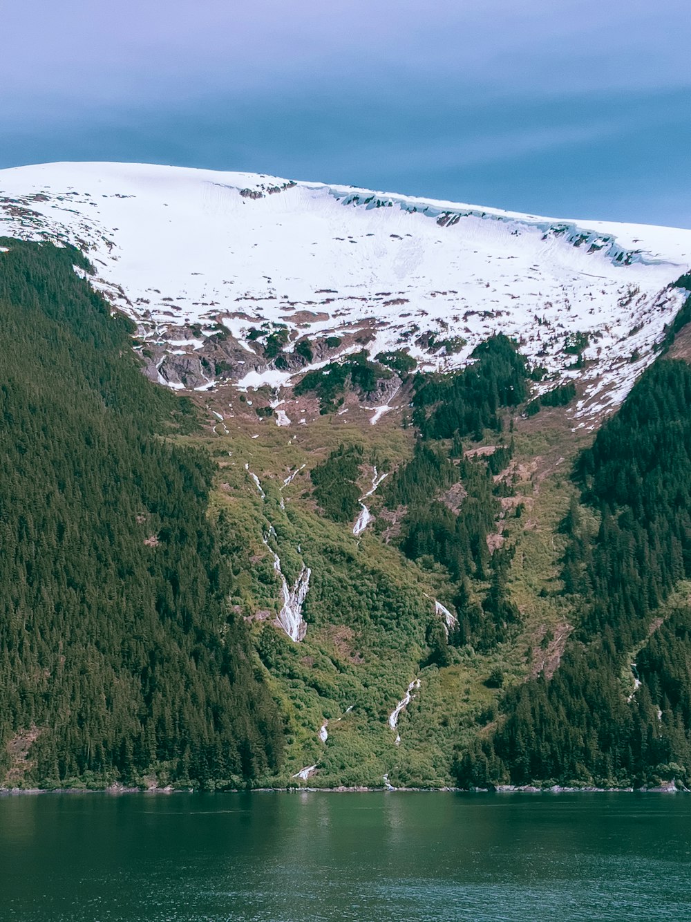 a mountain covered in snow next to a body of water