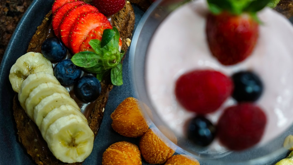 a plate of food with bananas, strawberries, kiwis and yogur