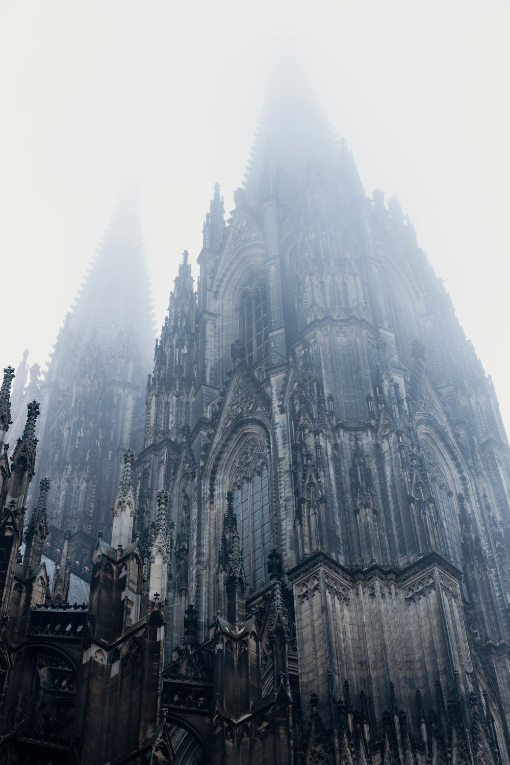 a very tall cathedral towering over a city on a foggy day