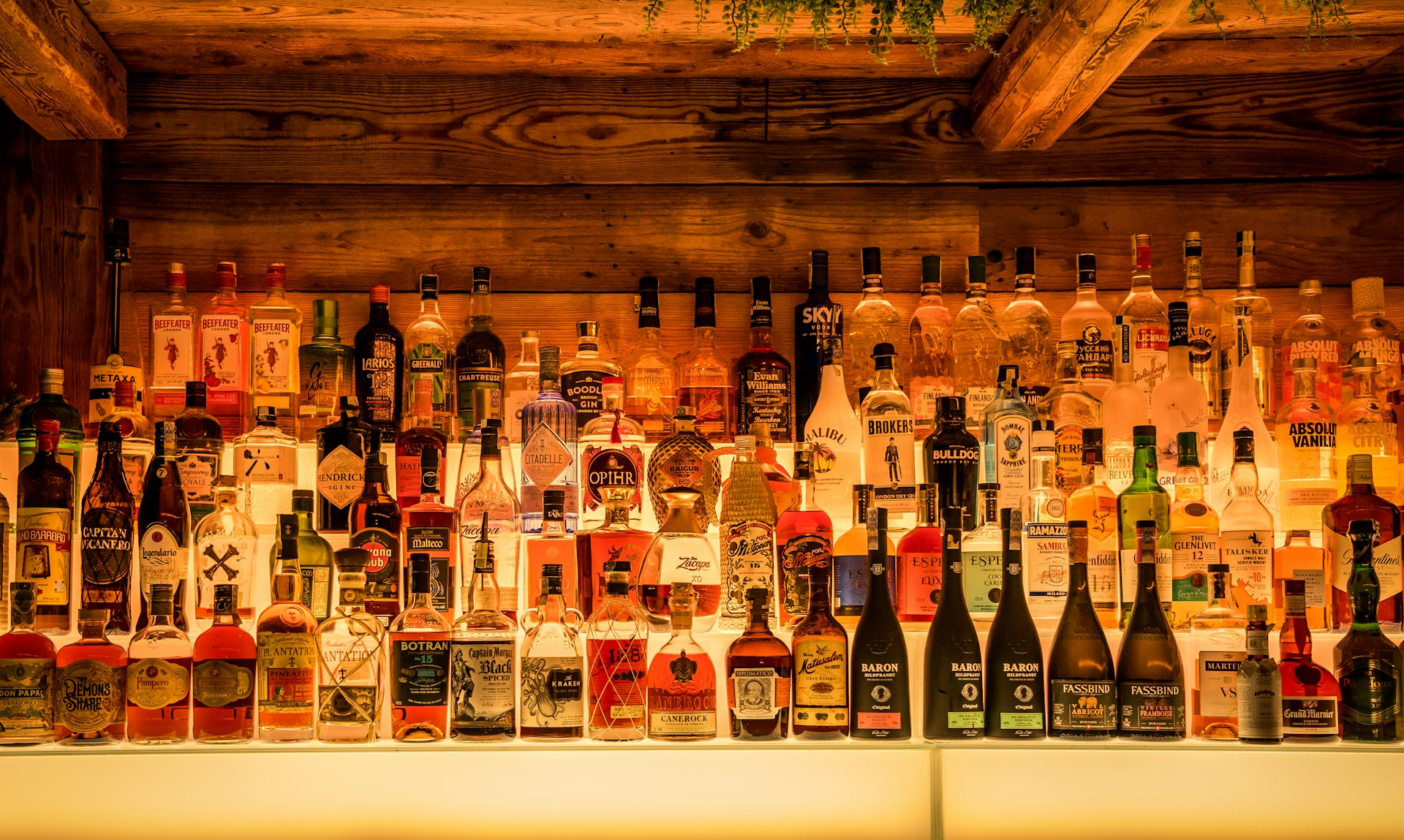 many bottles of alcohol are lined up on a wall