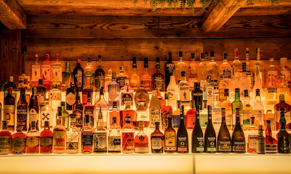 many bottles of alcohol are lined up on a wall