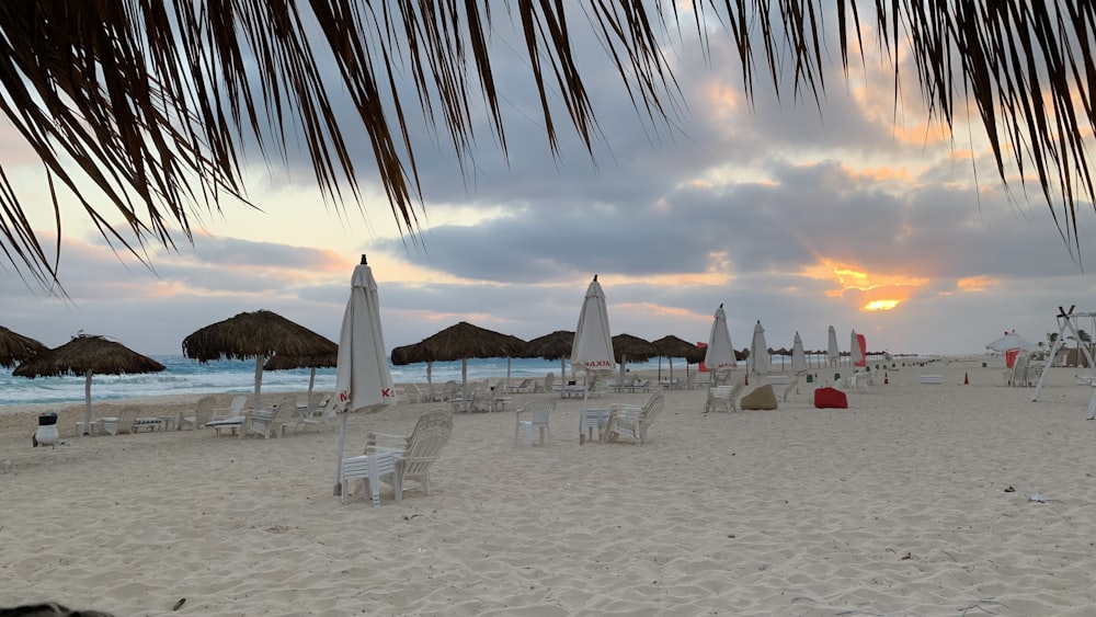 a sandy beach with umbrellas and chairs under a cloudy sky