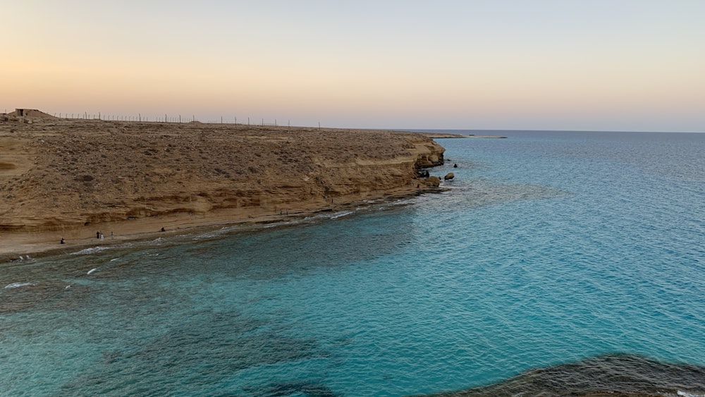 a body of water next to a rocky cliff