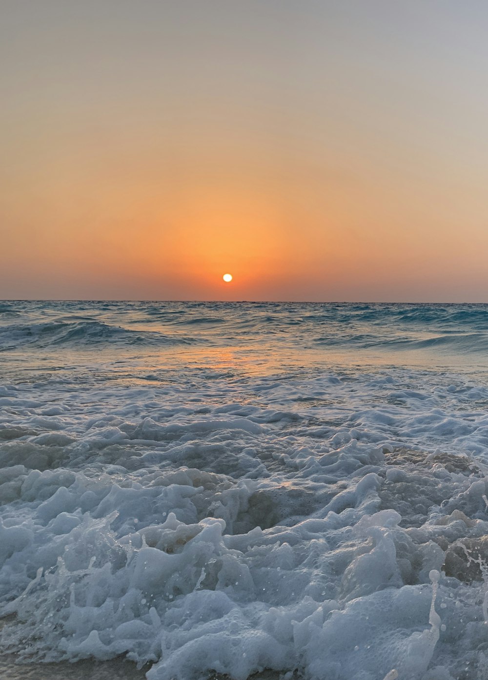 the sun is setting over the ocean waves