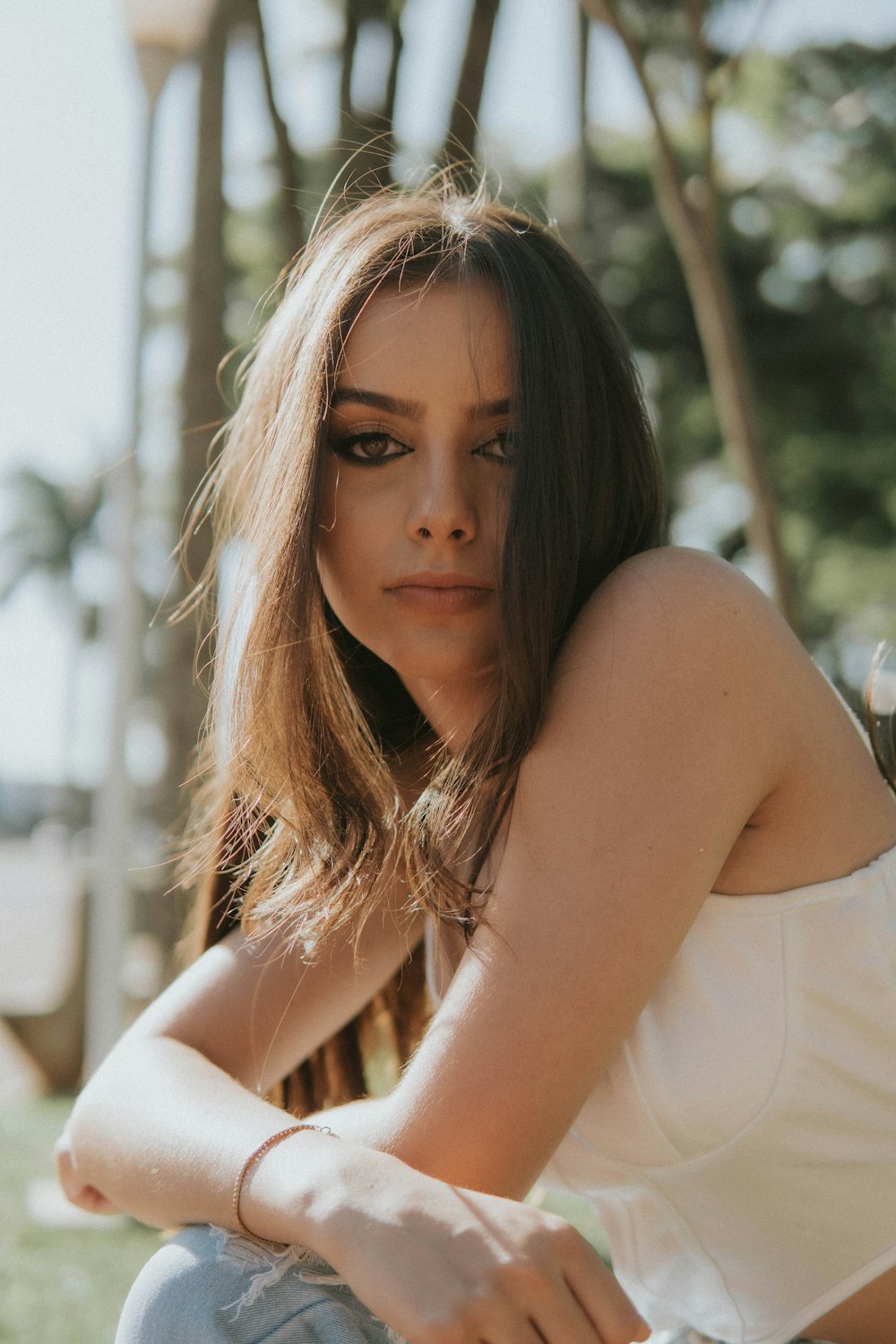 a woman sitting on the ground wearing a white top