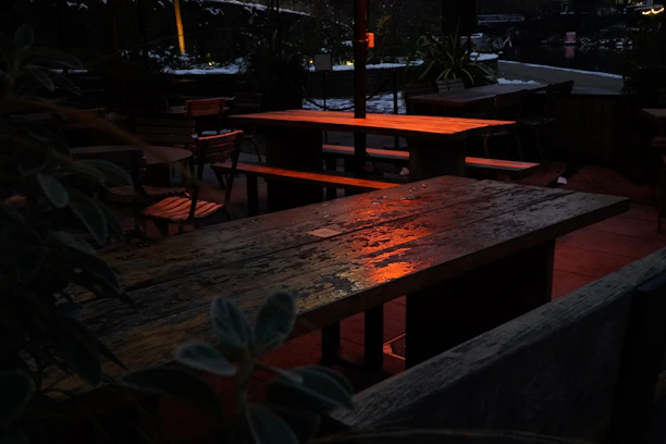 A softly lit outdoor patio featuring minimalist furniture and ambient yellow lighting creating a relaxing vibe.
