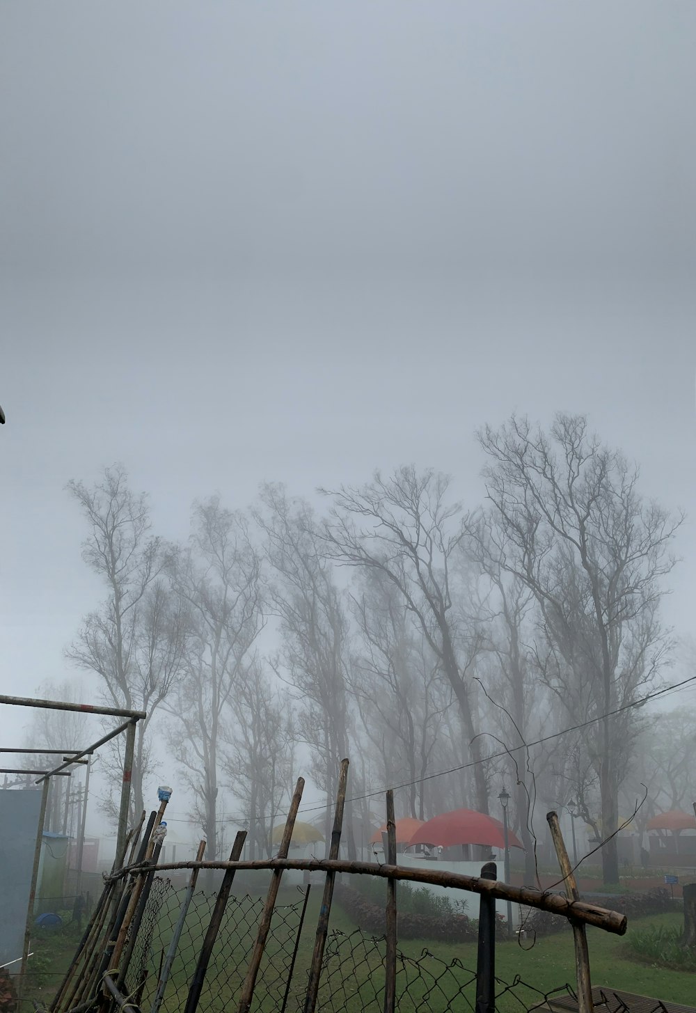 a fence with a red umbrella on a foggy day