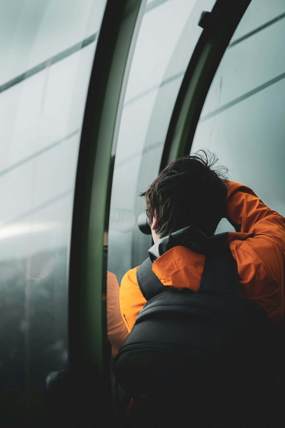 a man in an orange jacket sitting on a train
