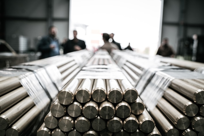 a group of people standing around a pile of metal rods