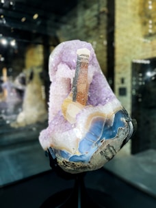 A vibrant amethyst geode glowing softly on a wooden shelf beside a small potted plant.