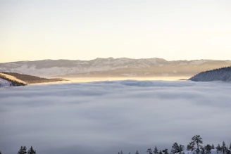 A serene sunrise over the snow-capped peaks of the Himalayan range, with lush green valleys below.