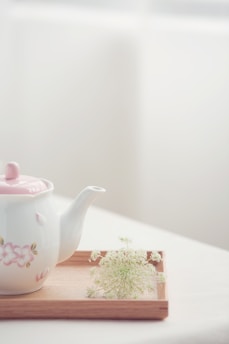 A serene close-up of a porcelain teapot steaming gently on a minimalist wooden table.