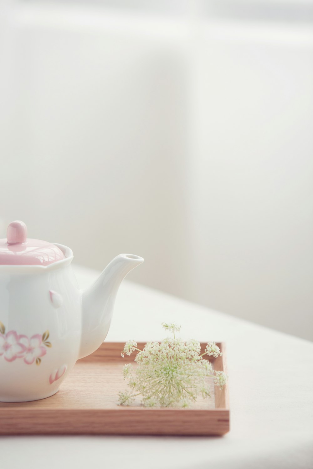 a tea pot with a pink lid sitting on top of a wooden tray