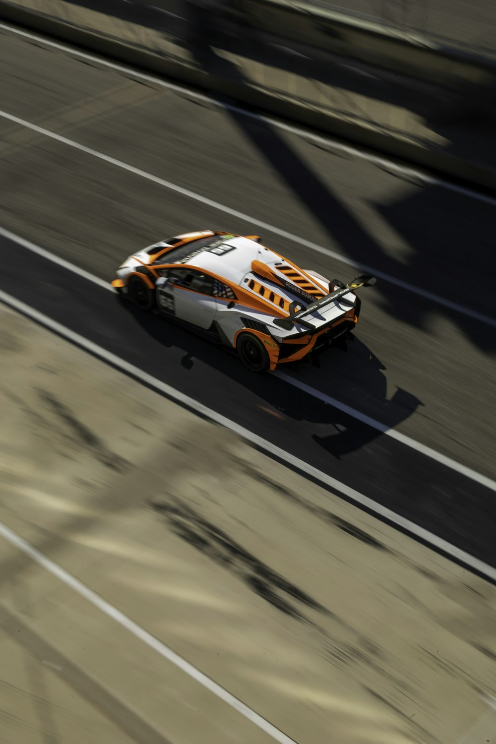 an orange and white car driving down a street