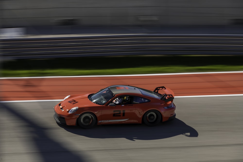 an orange sports car driving down a race track