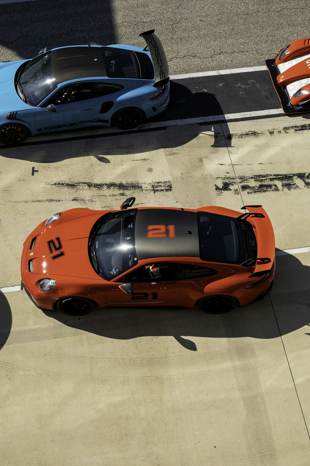 an orange sports car parked next to a blue sports car